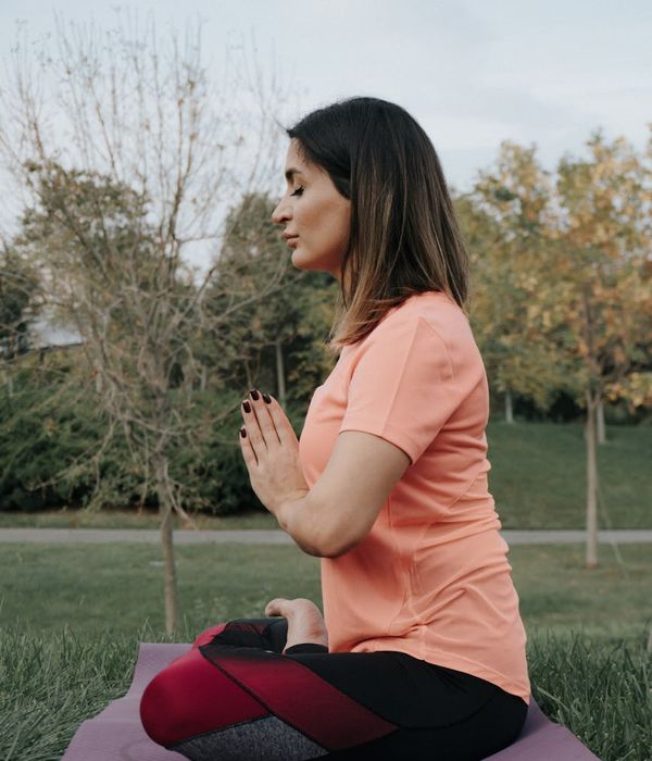 Woman performing a gentle stretching yoga pose outdoors.
